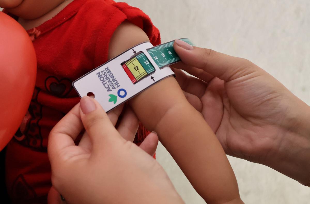 una enfermera comunitaria de Acción contra el Hambre mide el perímetro del brazo de una niña siria con desnutrición