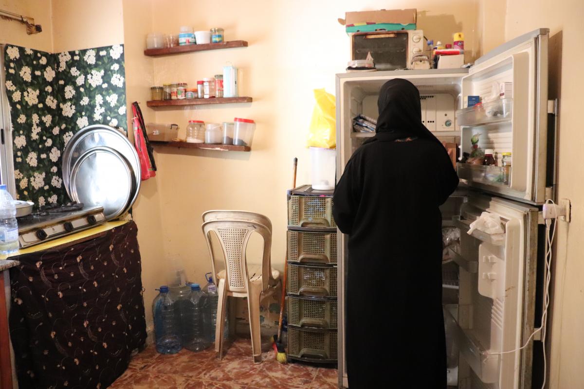 una mujer libanesa, con velo, en su cocina, donde el frigorífico no funciona por los cortes de luz
