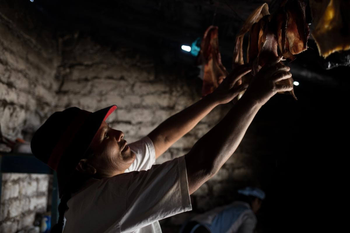 Mujer peruana poniendo la carne a secar para elaborar charqui 