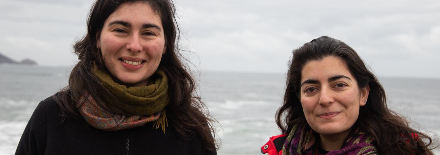 Dos mujeres sonríen a cámara frente al mar