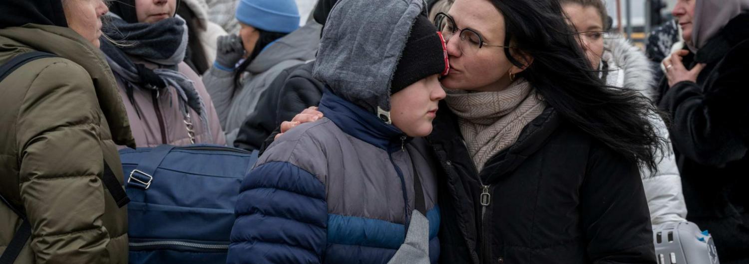 una madre refugiada besa a su hijo mientras esperan un autobús que los evacúe de Ucrania