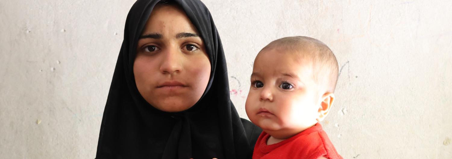 una madre siria sujeta a su bebé que sufre malnutrición moderada tras recibir tratamiento de Acción contra el Hambre